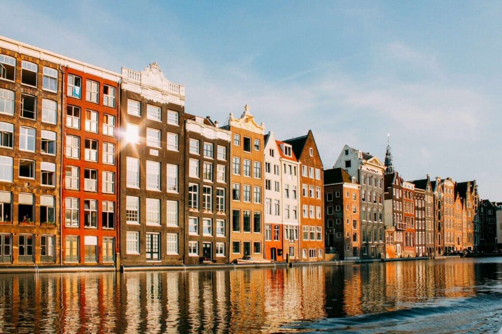 Amsterdam canal houses reflecting in the water at golden hour.
