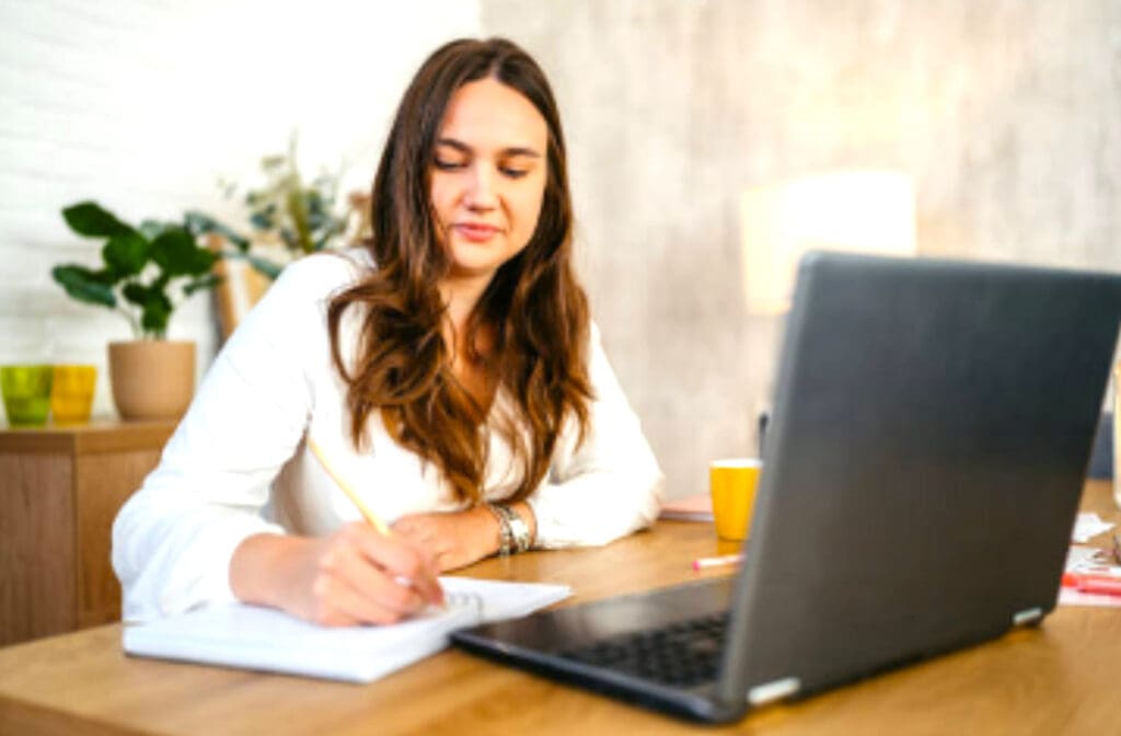 Femme concentrée écrivant à son bureau, utilisée pour illustrer l’apprentissage des techniques d’astrocartographie enseignées par Kristine Odegard.