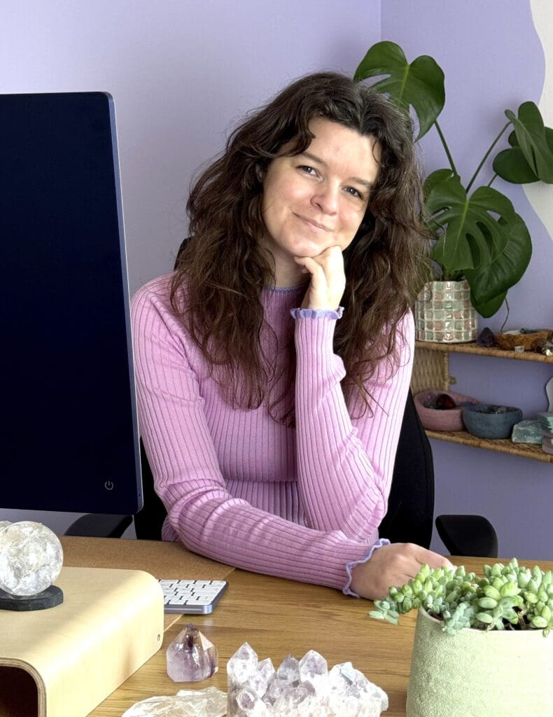 Portrait of Danish astrologer and astrocartographer Nynne Noël seated at her desk in her home office, surrounded by astrological tools and crystals.